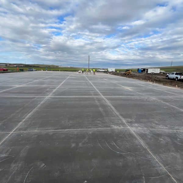 Large concrete slab at a commercial construction site with workers and equipment.