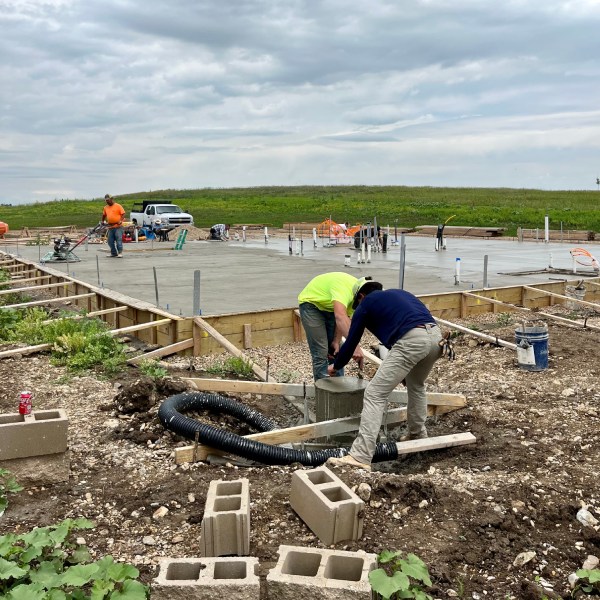 Workers installing a concrete foundation at a commercial construction site.