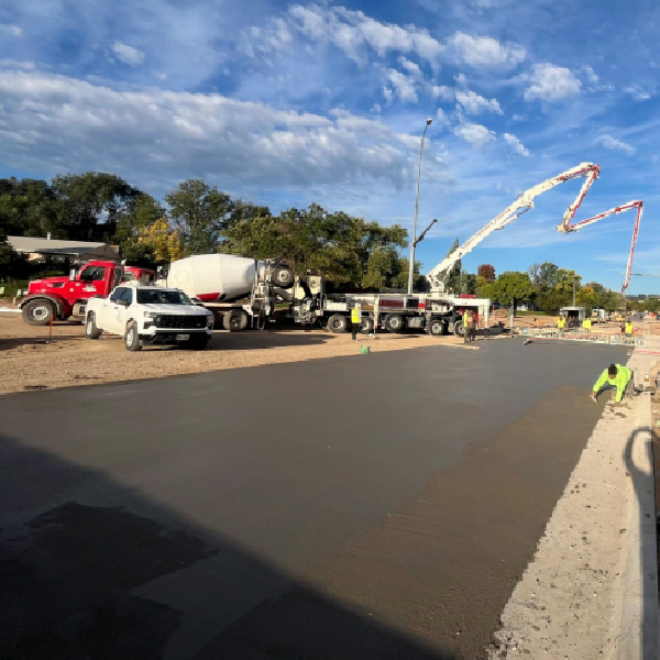 Workers pouring concrete using a boom pump truck at a commercial construction site.