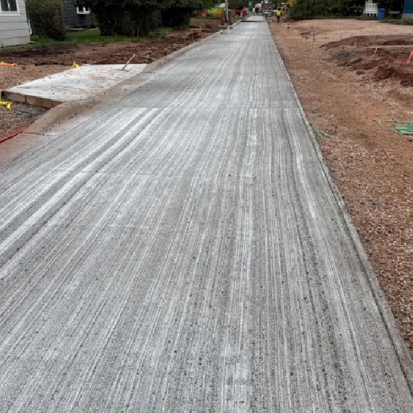 Newly finished concrete driveway with a textured surface at a residential construction site.